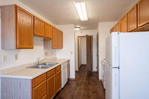 A kitchen with wooden cabinets and a white fridge. Fargo, ND Fieldstone Apartments