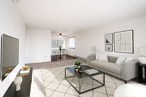 A living room with a grey couch, a black coffee table, and a television on the left side. Fargo, ND Fieldstone Apartments