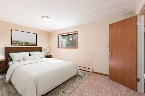 A bedroom with a large bed and a window. Bismarck, ND Parkview Arms Apartments