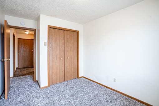 A room with a carpeted floor and a white wall. Fargo, ND Southgate Apartments
