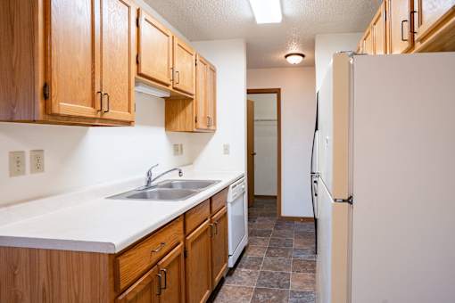 A kitchen with wooden cabinets and a white sink. Fargo, ND Southgate Apartments