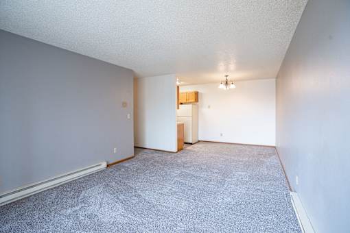 A room with a carpeted floor and a small wooden cabinet. Fargo, ND Southgate Apartments