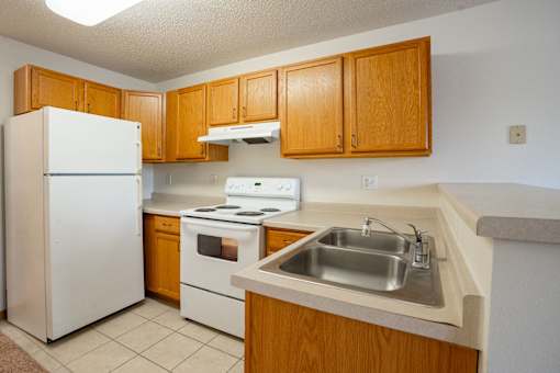 A kitchen with a white refrigerator, white stove, and a white sink. Fargo, ND Summit Point