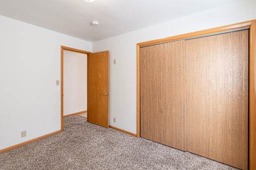 A room with a brown door and a brown wardrobe. Fargo, ND L&R Apartments