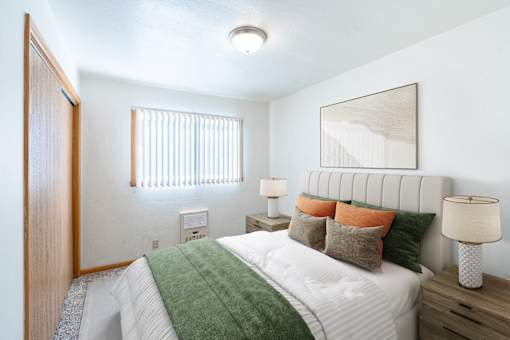 A bedroom with a bed, two lamps, and a mirror. Fargo, ND L&R Apartments