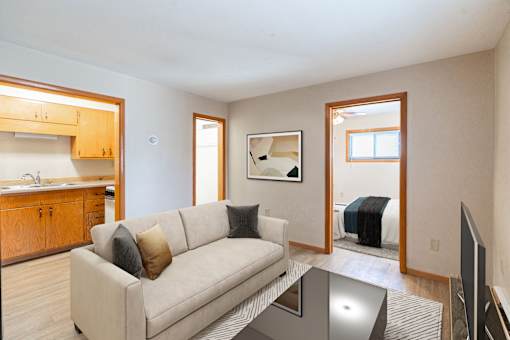 A living room with a couch, a coffee table, and a television. Fargo, ND Birchwood Apartments