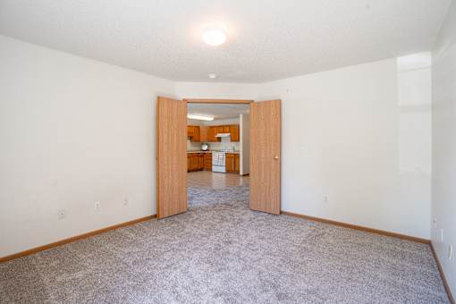 A room with a carpeted floor and a doorway leading to another room. Fargo, ND Stonebridge Apartments