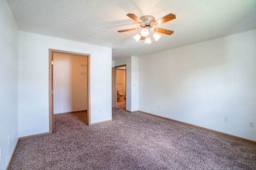A room with a ceiling fan and carpeted floor. Fargo, ND Stonebridge Apartments