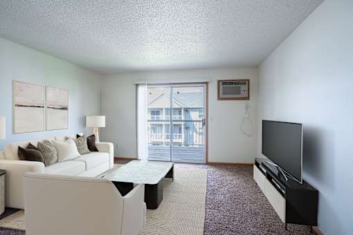 A living room with a white couch and a flat screen TV. Fargo, ND Stonebridge Apartments