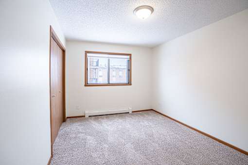 A room with a carpeted floor and a window. Fargo, ND Westwood Estates