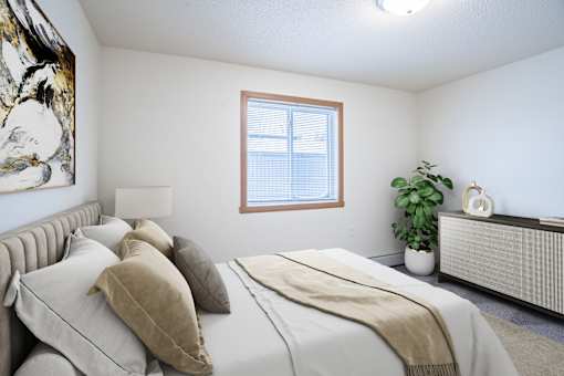 A bedroom with a large bed and a window. Moorhead, MN Woodstone Apartments