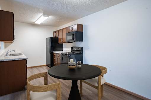 A black table with a vase on it sits in the middle of a kitchen. Moorhead, MN Woodstone Apartments
