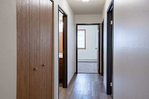 A hallway with a wooden door on the left and a black door on the right. Moorhead, MN Woodstone Apartments