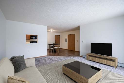 A living room with a couch, coffee table, and television. Moorhead, MN Woodstone Apartments