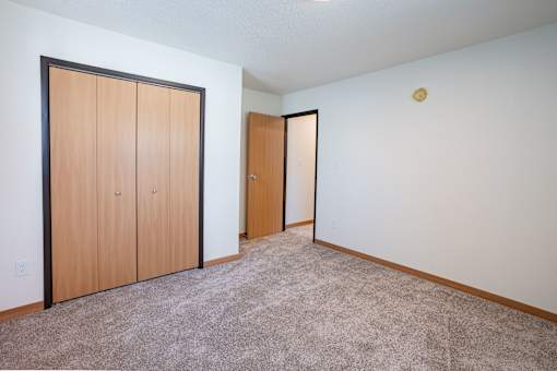 A room with carpeted floor and two doors. Cherry Creek Apartments