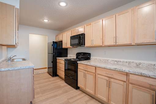 A kitchen with wooden cabinets and black appliances. Cherry Creek Apartments