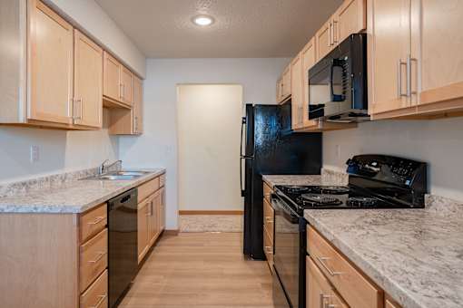 A kitchen with wooden cabinets and black appliances. Cherry Creek Apartments
