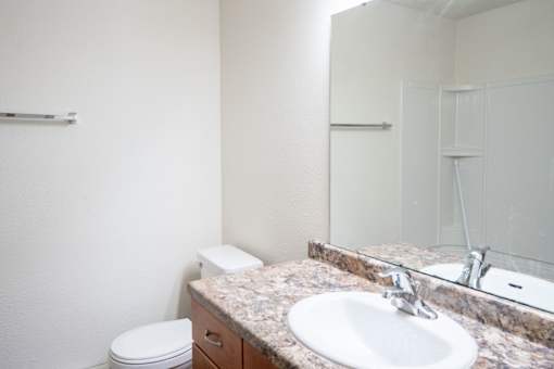 A bathroom with a toilet, sink and mirror. Fargo, ND Kennedy Apartments