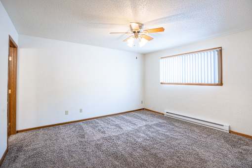 A room with a ceiling fan and a window with blinds. Fargo, ND Kennedy Apartments