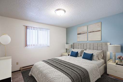 A bedroom with a large bed and a window with blinds. Fargo, ND Countryside Apartments
