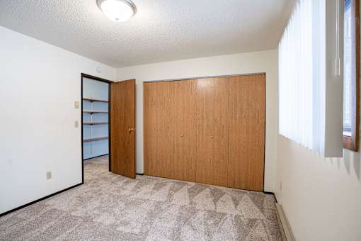 A room with a carpeted floor and two wooden doors.