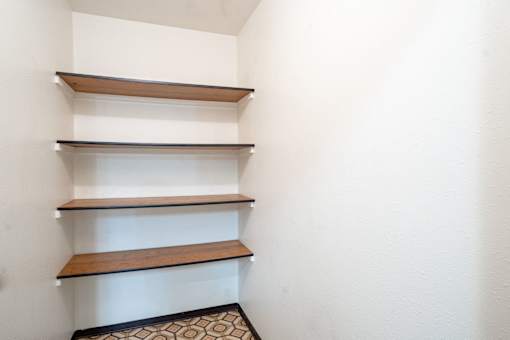 A white wall with three shelves and a black and white floor.