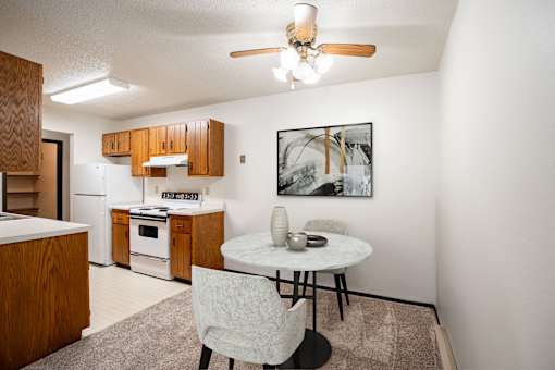 A kitchen with a table and chairs and a framed picture on the wall. Fargo, ND Countryside Apartments