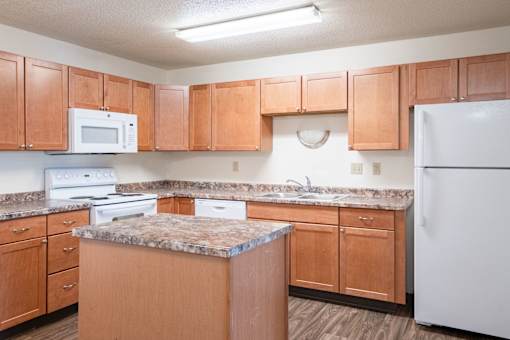 A kitchen with wooden cabinets and a granite countertop. Fargo, ND Kennedy Apartments