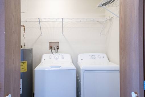 Two white front loading washing machines in a small laundry room. Fargo, ND Kennedy Apartments