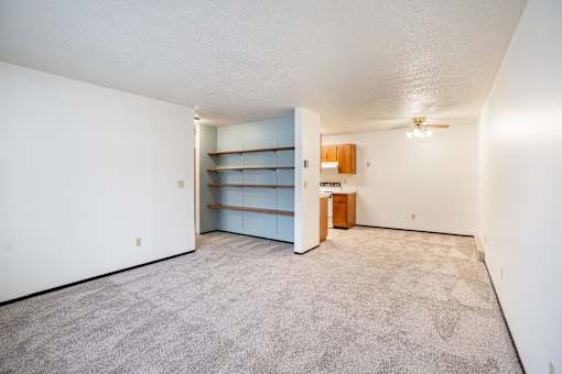 A room with a carpeted floor and a ceiling fan.