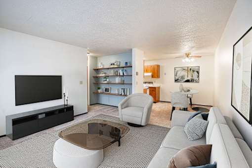 A living room with a grey sofa, a glass coffee table, and a television. Fargo, ND Countryside Apartments