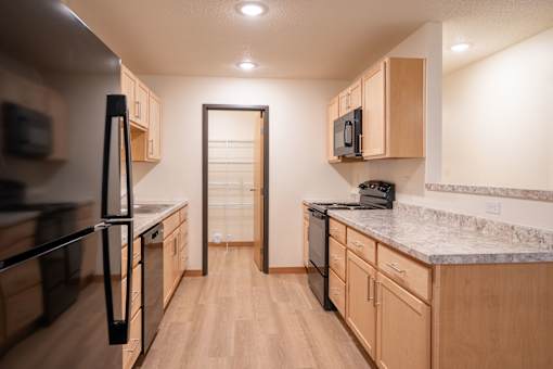 A kitchen with wooden cabinets and a marble countertop. Cherry Creek Apartments