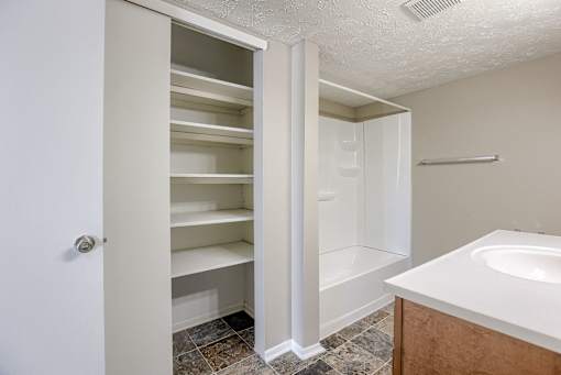 A white bathroom with a walk-in shower and a white sink. Omaha, NE Evergreen Terrace Apartments