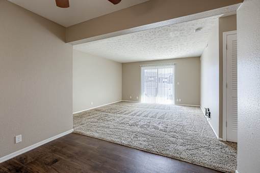 A room with a rug on the floor and a window with blinds. Omaha, NE Evergreen Terrace Apartments