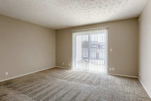 A room with a carpeted floor and a sliding glass door. Omaha, NE Evergreen Terrace Apartments