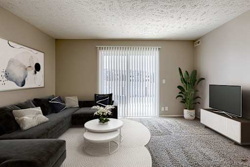 A living room with a grey couch, a white coffee table, and a painting on the wall. Omaha, NE Evergreen Terrace Apartments