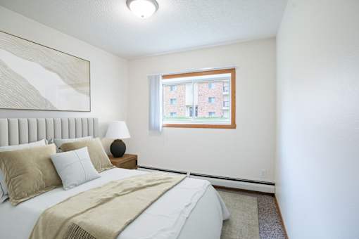 A bedroom with a large bed and a window. Grand Forks, ND Columbia West Apartments