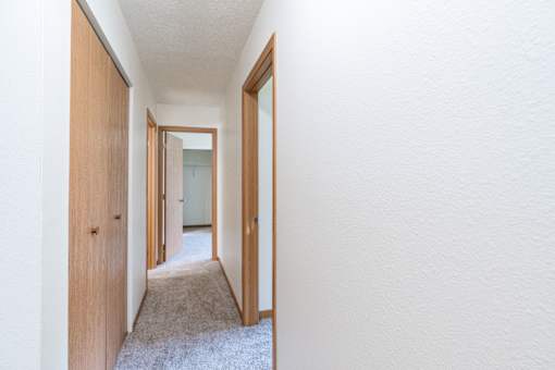 A hallway with white walls and a carpeted floor. Grand Forks, ND Columbia West Apartments