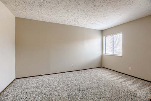 A room with a window and carpeted floor. Omaha, NE Stony Brook Apartments