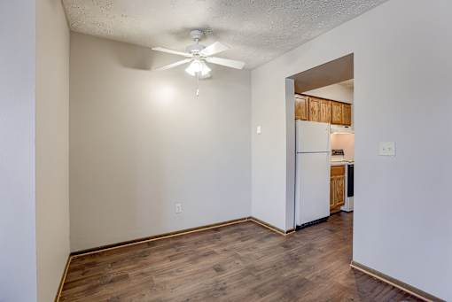 A room with a ceiling fan and a kitchen in the background. Omaha, NE Stony Brook Apartments