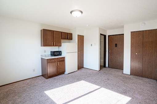 A kitchen with white appliances and brown cabinets. Fargo, ND Pacific Park I Apartments