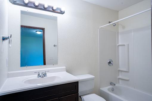 A white bathroom with a white sink and a white toilet. Fargo, ND Hartford Apartments