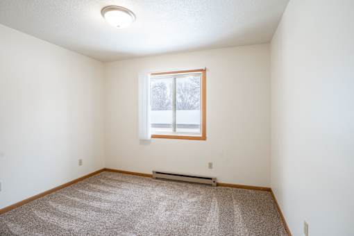 A room with a carpeted floor and a window. Fargo, ND Long Island Apartments