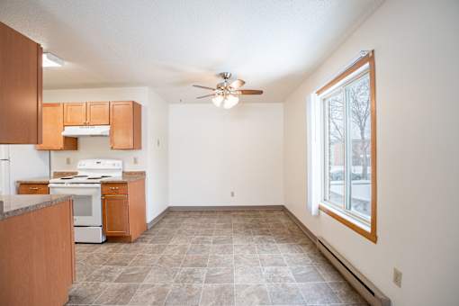 A kitchen with brown cabinets and a tiled floor. Fargo, ND Long Island Apartments