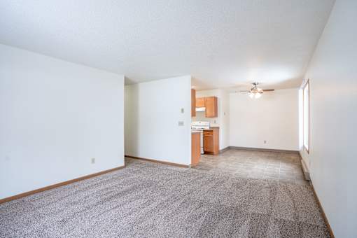 A room with a carpeted floor and a ceiling fan. Fargo, ND Long Island Apartments