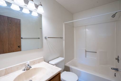 A white bathroom with a sink, toilet, and bathtub. Fargo, ND West Oak Apartments