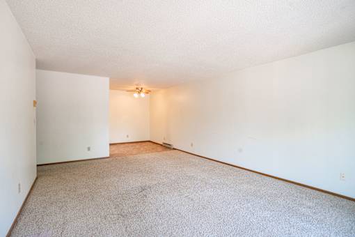A large, empty room with a carpeted floor and a light on. Fargo, ND West Oak Apartments