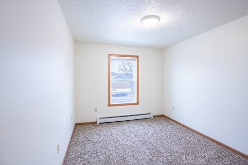 A room with a window and a car parked outside. Fargo, ND Park Place Apartments