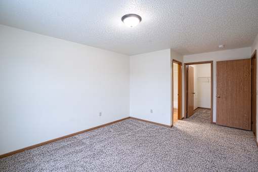 A room with a carpeted floor and a ceiling light. Fargo, ND Park Place Apartments
