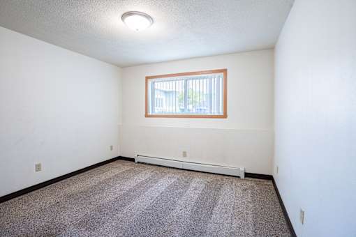 A room with a window and a carpeted floor. Fargo, ND Islander Apartments